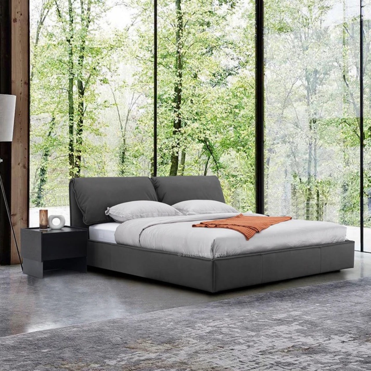 Modern bedroom with a gray upholstered bed and large windows showing greenery.